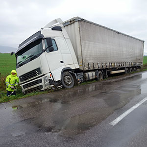 The 18-wheeler truck overturned in a field on the side of the road.