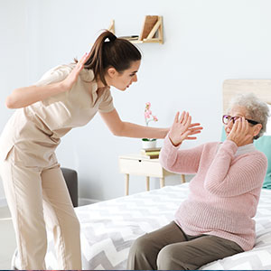 Home nurse raising hand to hit elderly woman, symbolizing nursing home negligence.