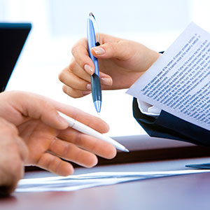 Hands holding pens and reviewing documents at a desk symbolize what question should be asked to personal injury attorney. - Porter & Guidry Law Firm